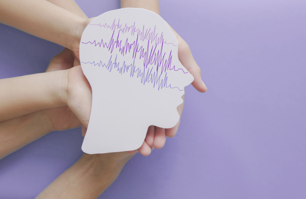 Image shows numerous hands holding a white cutout of a face with brain waves on a purple background.